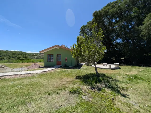 Cabaña verde en renta con jardín y bancas de piedra
